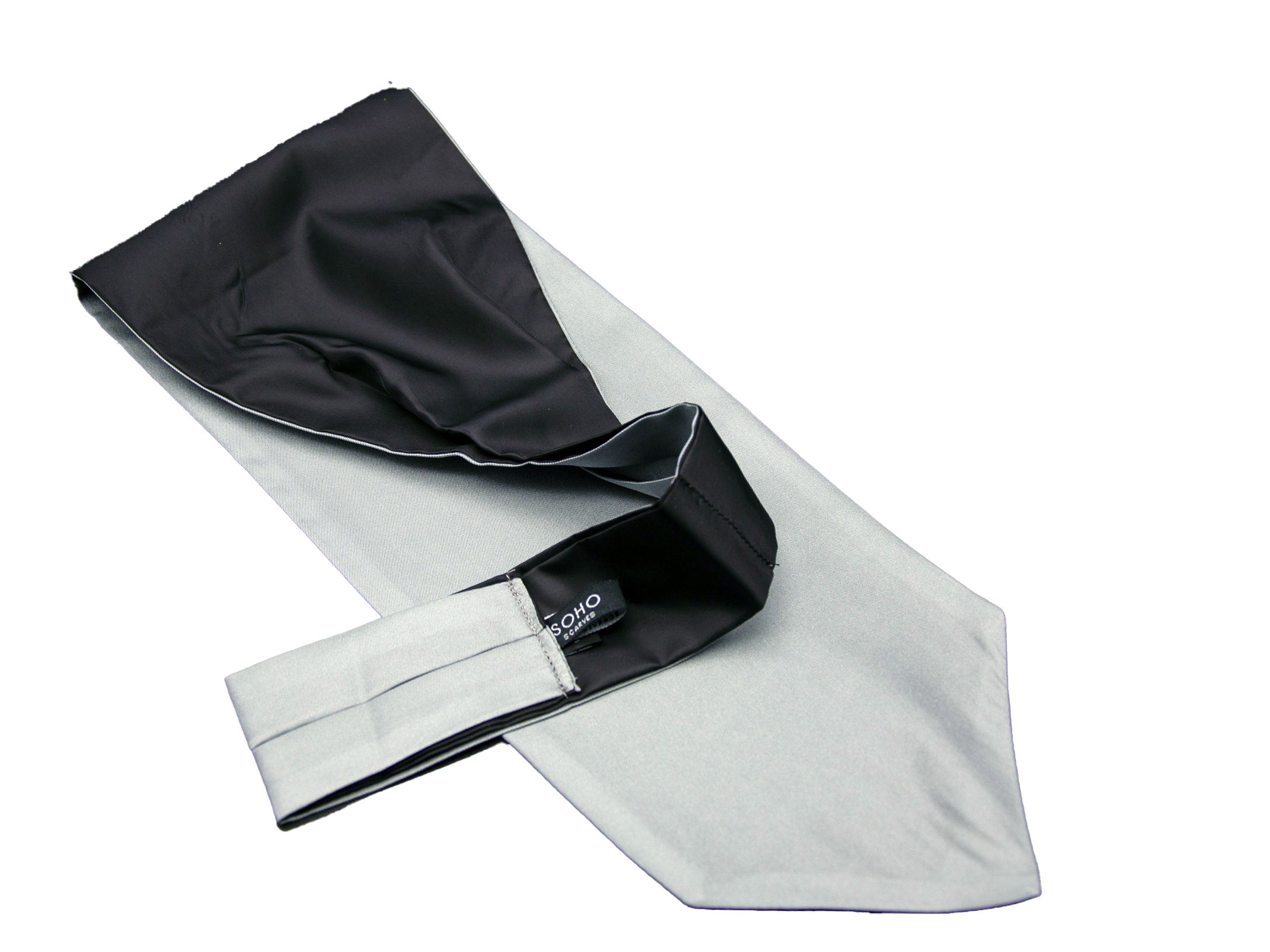 Pale grey 'Bilbao' single pointed Ascot tie arranged diagonally with wide point in foreground. Narrow end of tie folded back and over to reveal dark lining. Placed on white background.