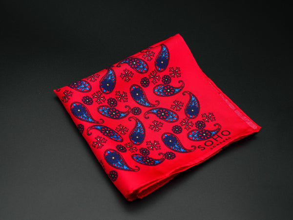 Pure silk 'Casablanca' pocket square folded showing simple blue paisley 'tears' interdispersed with decorative floral patterns on a vibrant red ground. SOHO Scarves branding clearly visible on bottom-right.