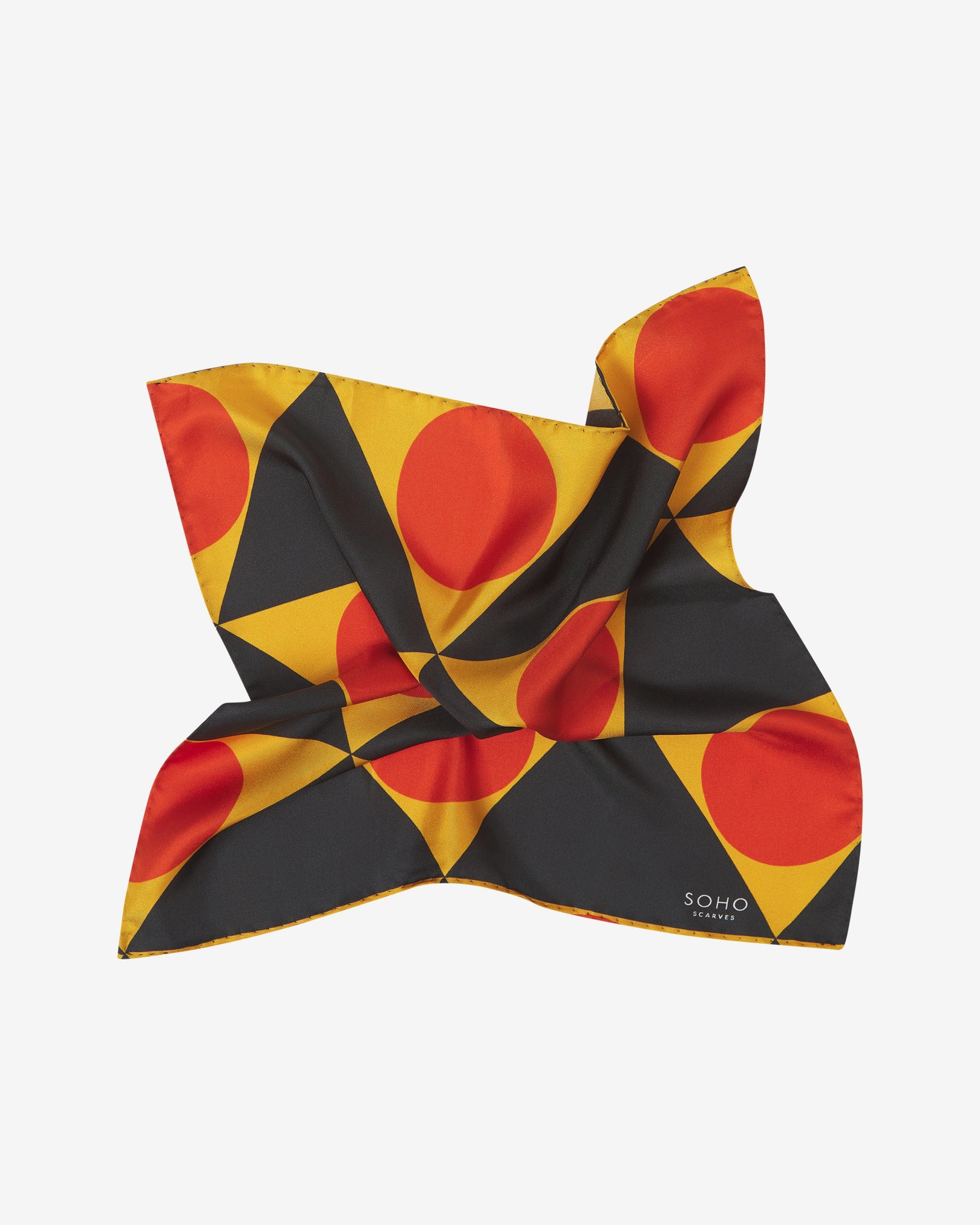 The 'Dresden' silk pocket square from SOHO Scarves, pinched in the middle and slightly twisted, showing the sheen of the silk material with the triangular and circular patterns.