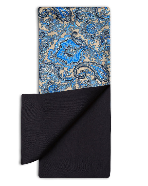 'The Piccadilly' dress scarf arranged in a rectangular shape clearly showing the dark, mid and light blue paisley patterns. The bottom-right quadrant is folded back to reveal the fine woollen lining underneath the pure silk exterior.