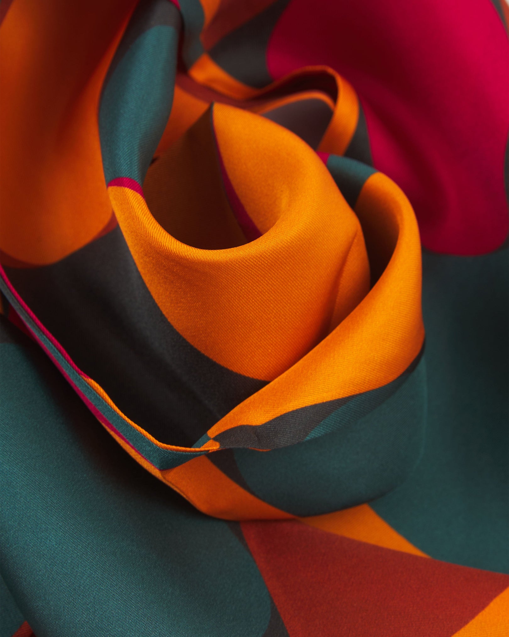 A ruffled close-up of the 'Essen' silk scarf, presenting a closer view of the multicoloured, Bauhaus inspired patterns.