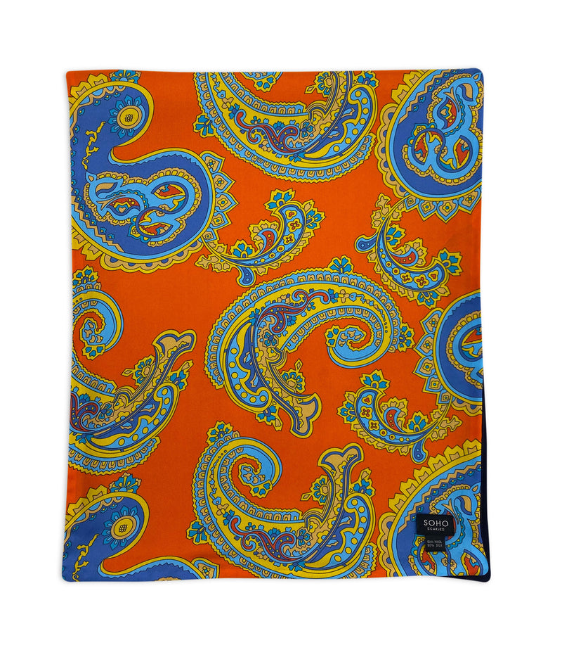 'The Orange Wide' arranged in a square shape showing the array of blue paisley patterns on a vibrant orange background. Also showing the 'SOHO Scarves' branding label.
