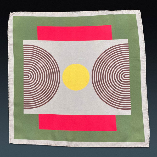 Fully unfolded 'Tay' silk pocket square, showing the geometric patterns in red, brown and yellow, set on a green background and framed with a cream-coloured border.