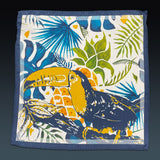 Fully unfolded 'Tees' silk pocket square, showing the stylised toucan bird motif against a tropical backdrop, framed with a blue border.