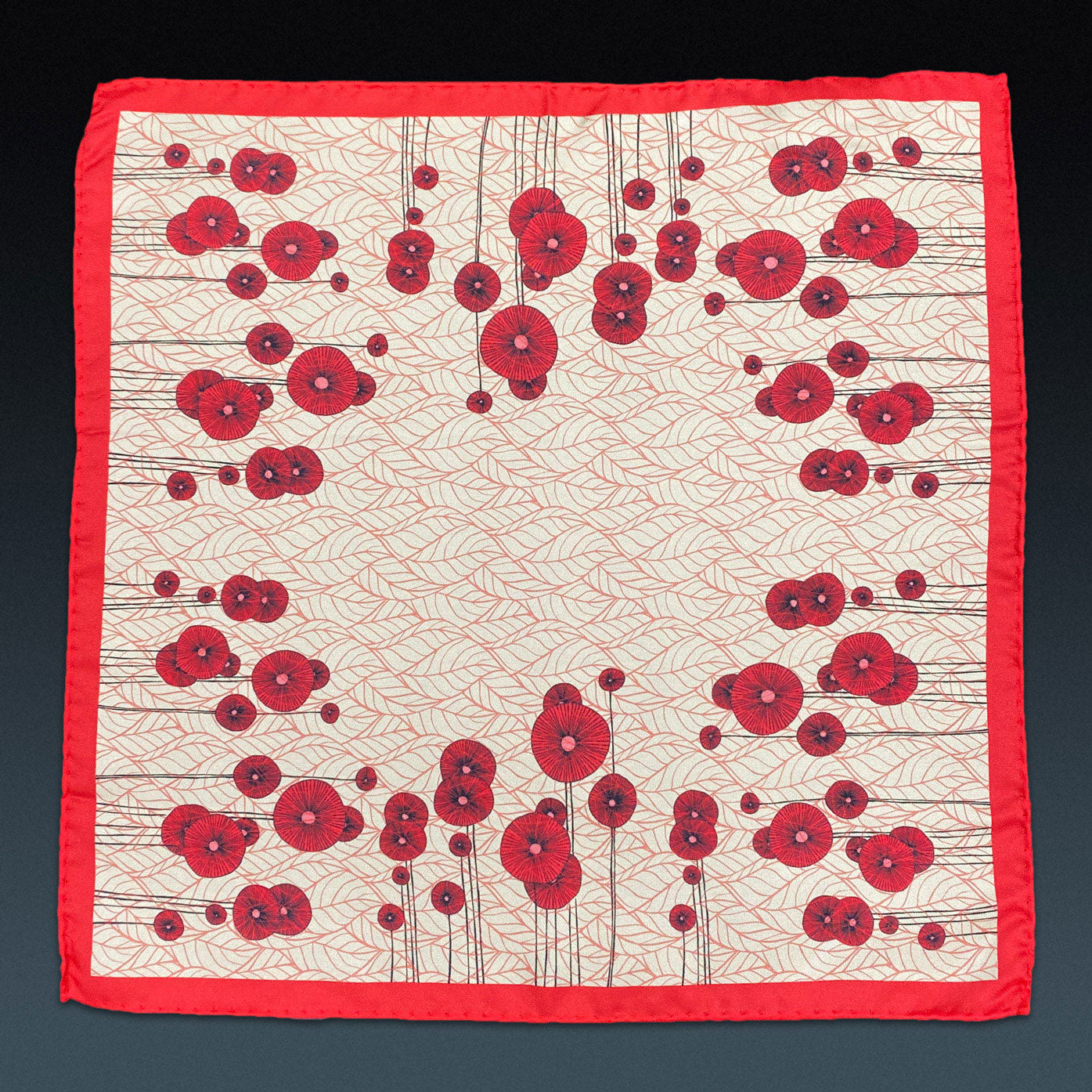 Fully unfolded 'Thames' silk pocket square, showing the stylised red poppy flowers, set on a subtle leaf-textured repeat background.