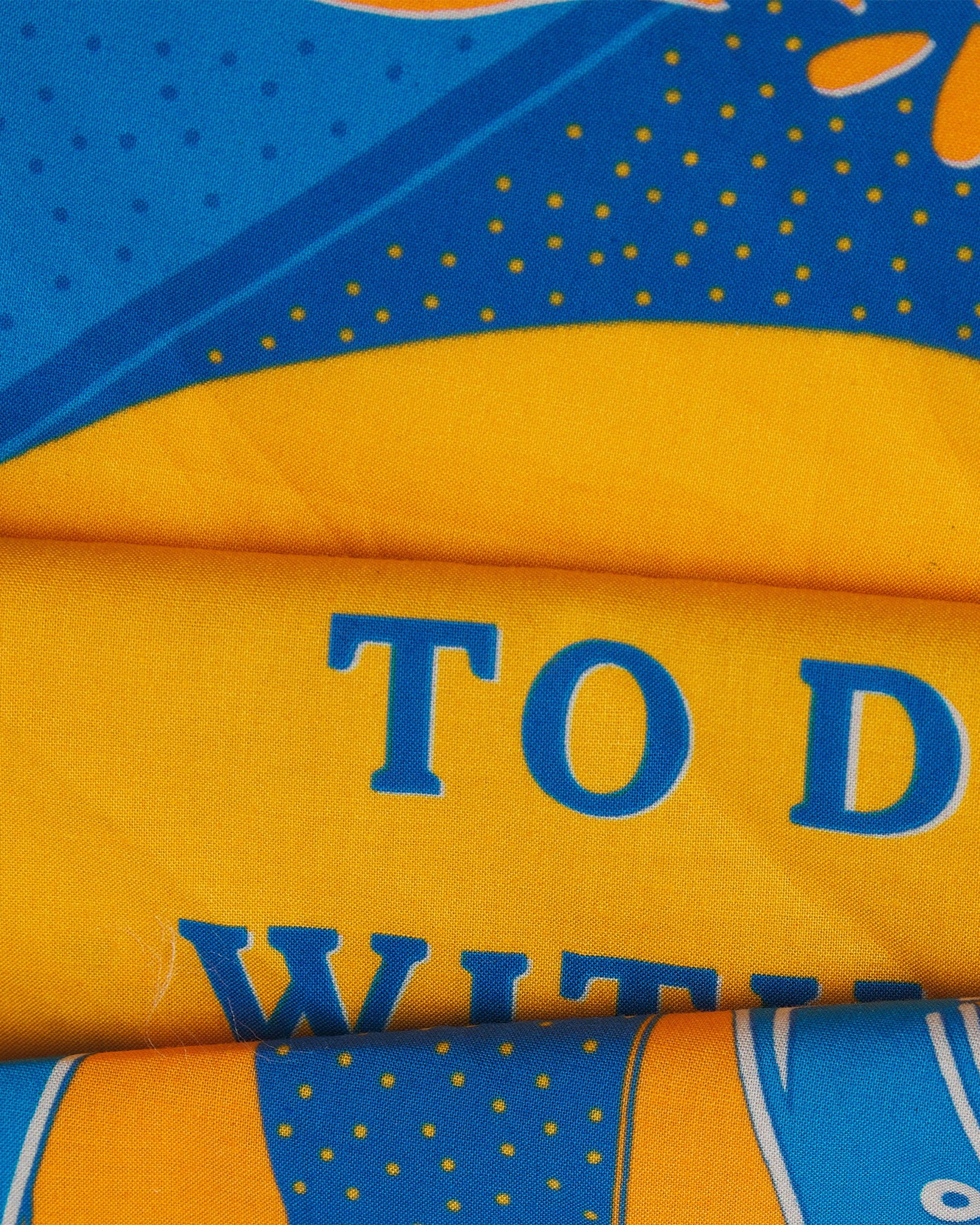 A ruffled, close-up view of the yellow and blue 'Luck' Old West-style bandana from Soho Scarves.