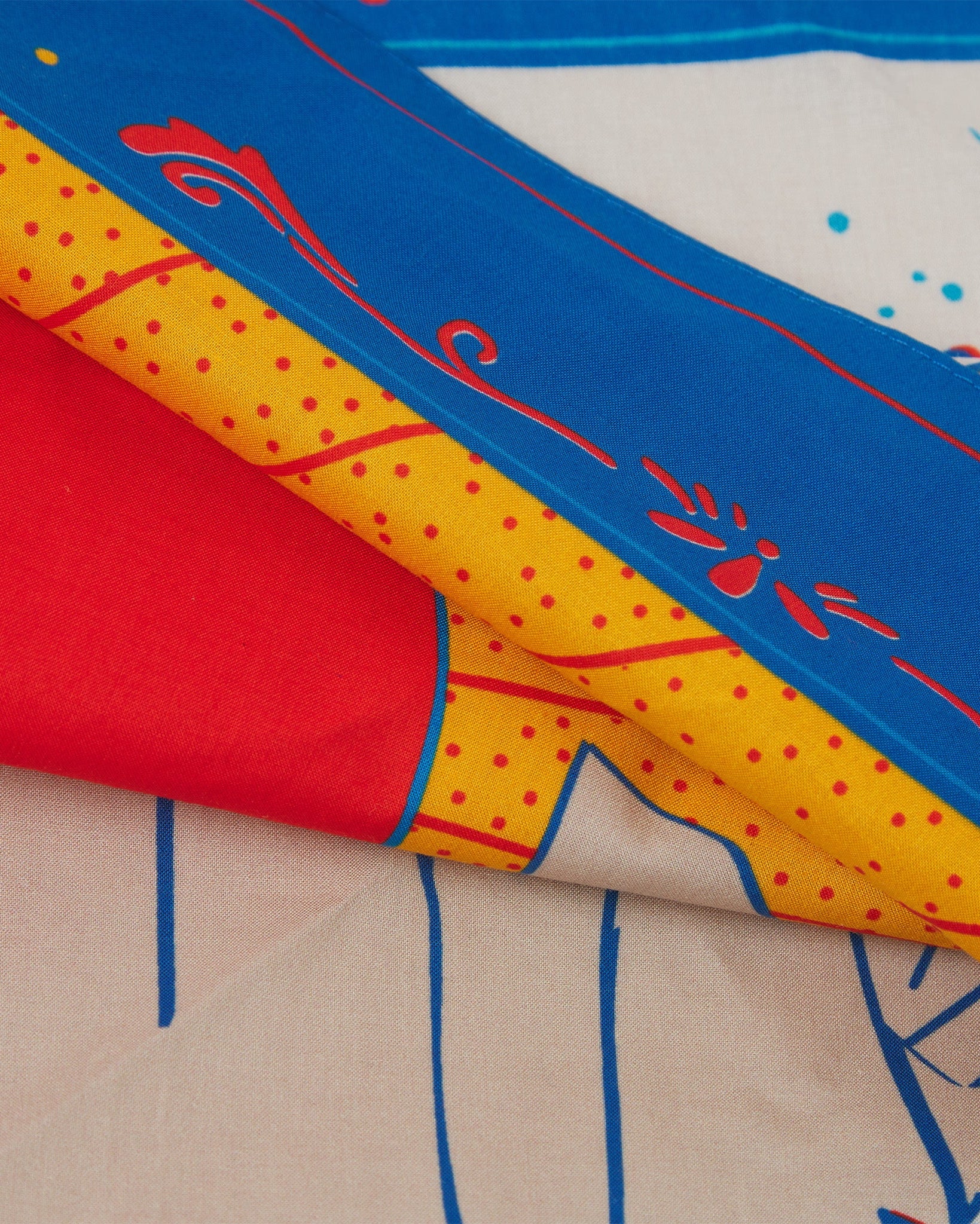 A ruffled, close-up view of the red, blue, yellow and white 'Respect' Old West-style bandana from Soho Scarves.