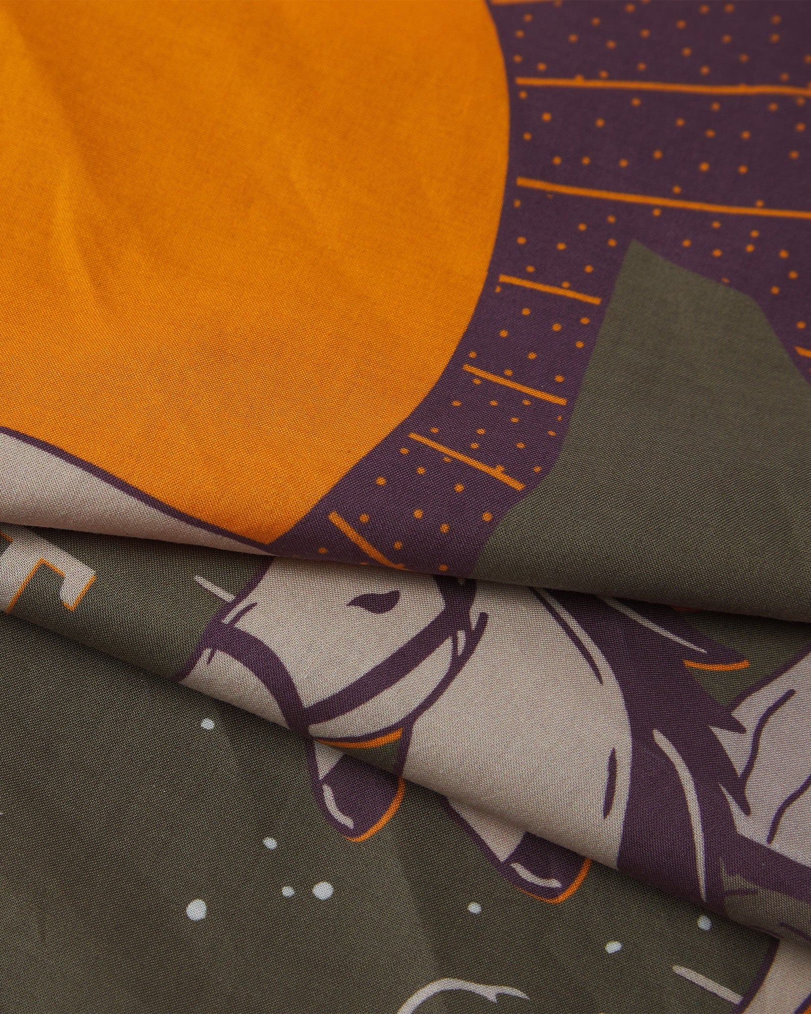 A ruffled, close-up view of the khaki, burgundy and cream 'Respect' Old West-style bandana from Soho Scarves, with a focus on the bright orange sunshine.