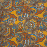 A flat, folded view of 'The Carnaby' bandana. Clearly showing the large swirls of paisley patterns on a gold-yellow background.