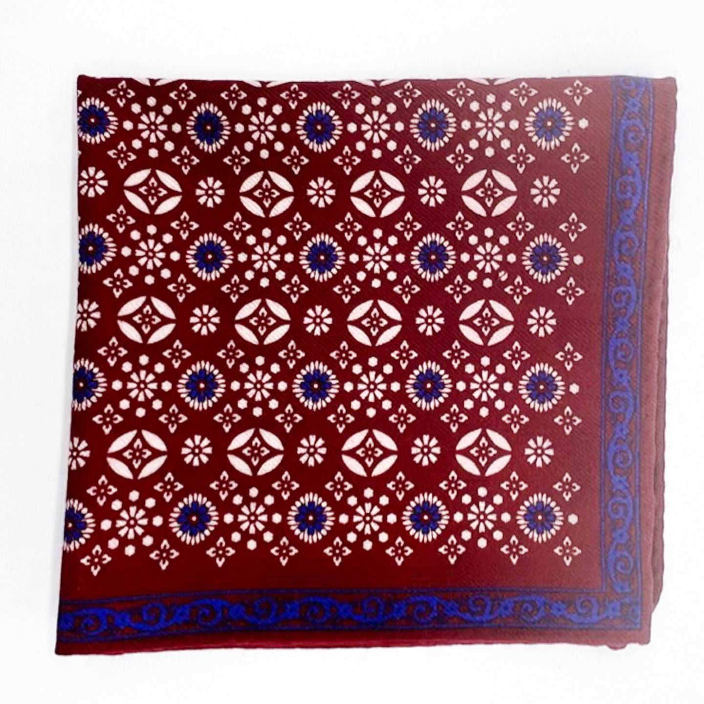 Pure wool 'Hampi' pocket square folded into a quarter and placed on a white background, showing white and blue decorative floral patterns on a red ground.