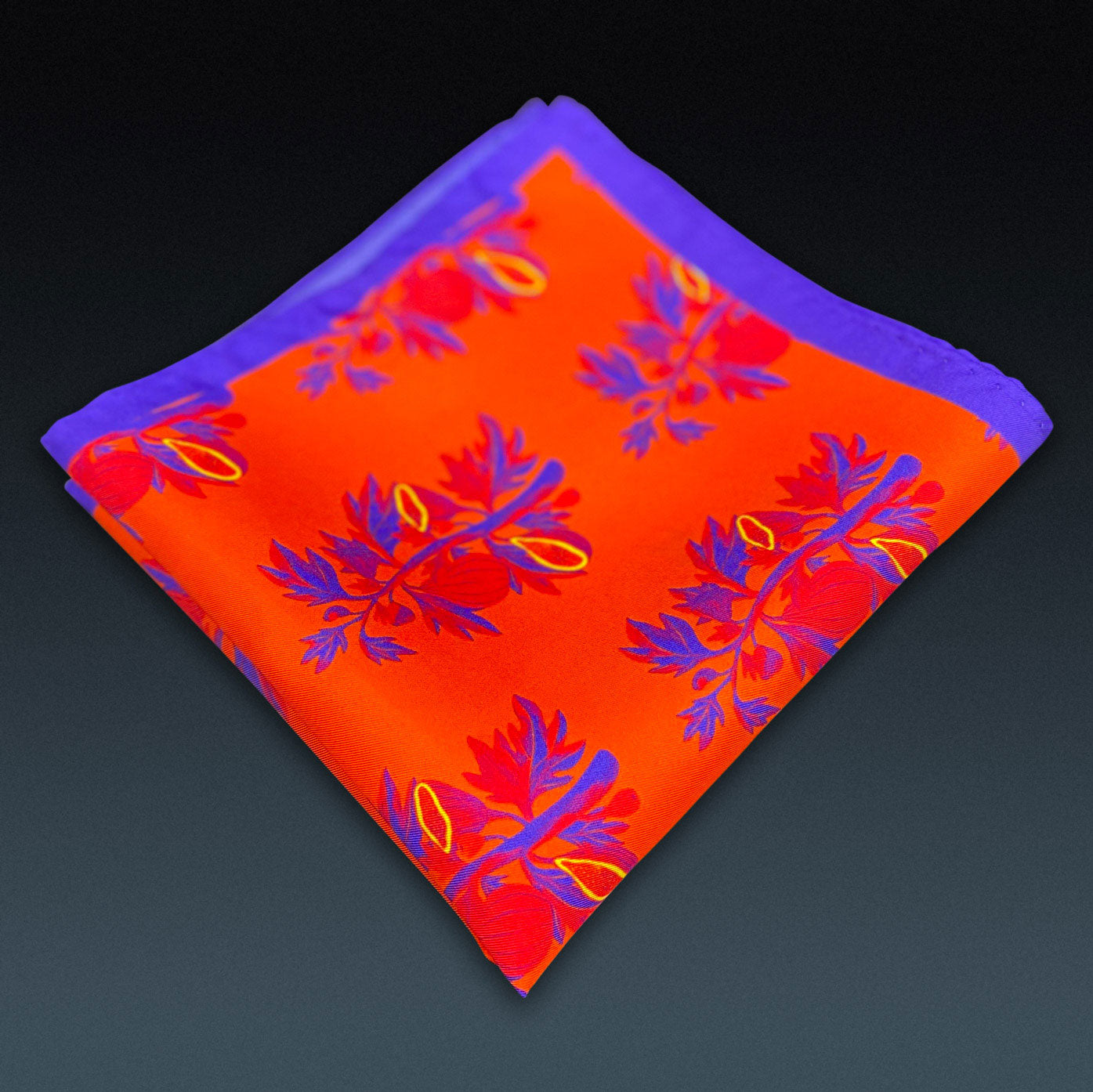 Folded 'Severn' silk pocket square from SOHO Scarves, showing the tree branch repeat motif. Placed on a dark background.