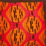 A flat, folded view of 'The Sierra' bandana. Clearly showing the primitive Aztec inspired pattern in red, orange and brown.