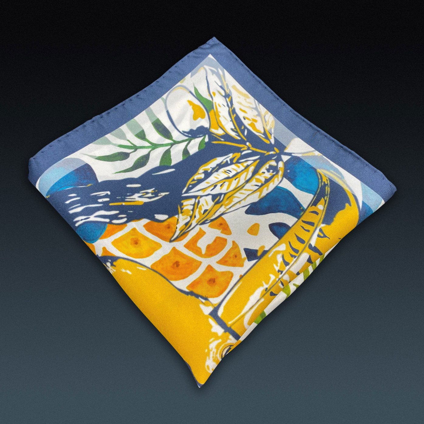 Folded 'Tees' silk pocket square from SOHO Scarves, showing the tropical silk screen pattern. Placed on a dark background.