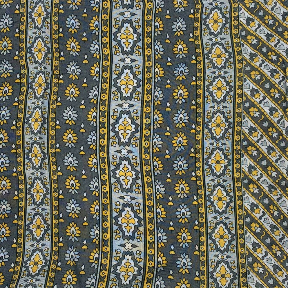 A flat, folded view of 'The Whitehorse' bandana. Clearly showing the decorative and floral-inspired patterns in yellow, grey and silver.