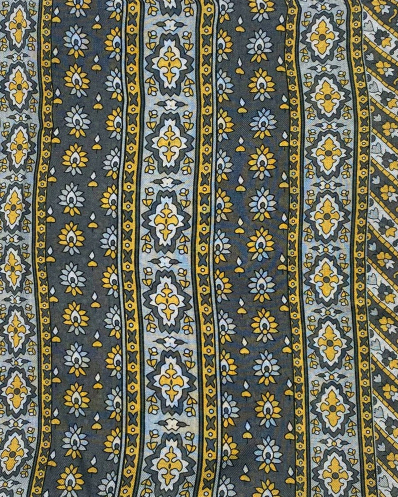 A flat, folded view of 'The Whitehorse' bandana. Clearly showing the decorative and floral-inspired patterns in yellow, grey and silver.