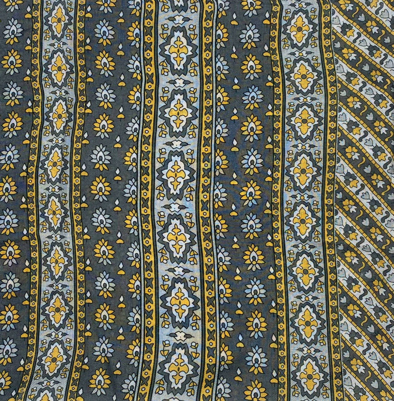A flat, folded view of 'The Whitehorse' boho wide scarf. Clearly showing the decorative and floral-inspired patterns in yellow, grey and silver.
