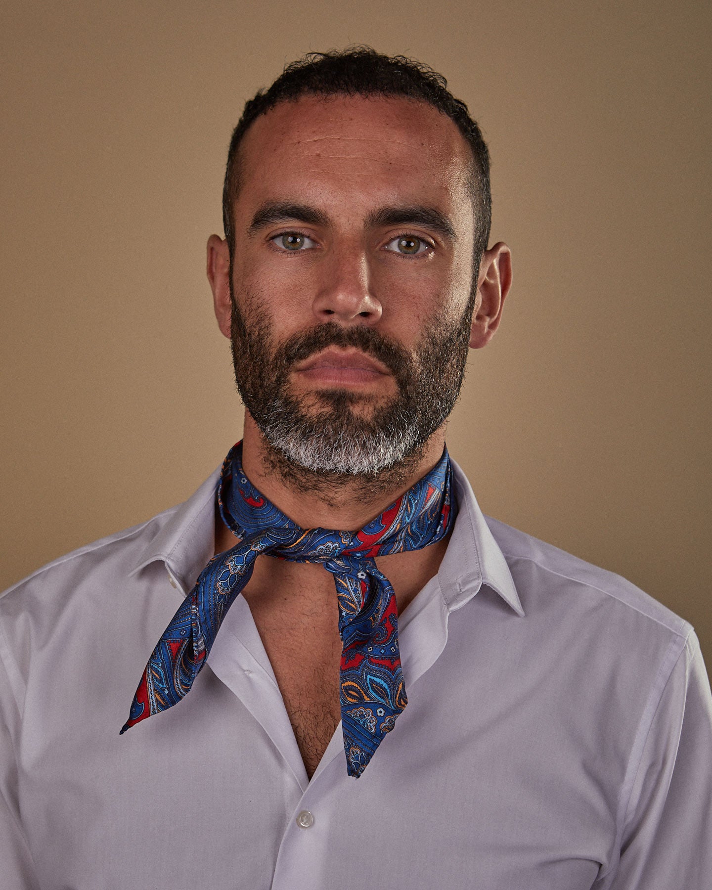 Portrait view of model looking straight ahead, wearing 'The Oxford' red and blue paisley neckerchief tied in a simple front-facing knot.