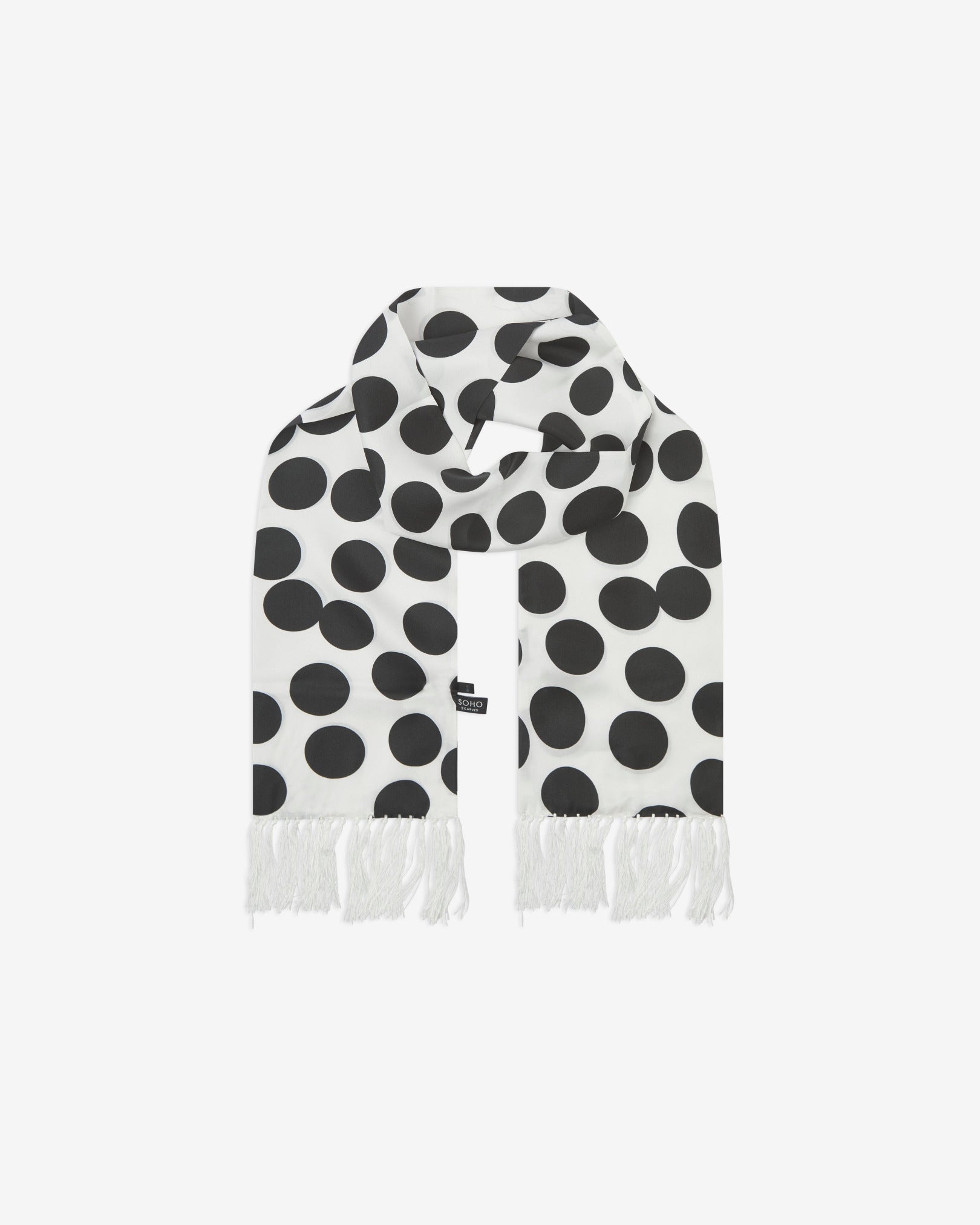 The Gable silk aviator scarf looped with both ends parallel to effectively display the white fringe and full repeat pattern of black discs on a white background.