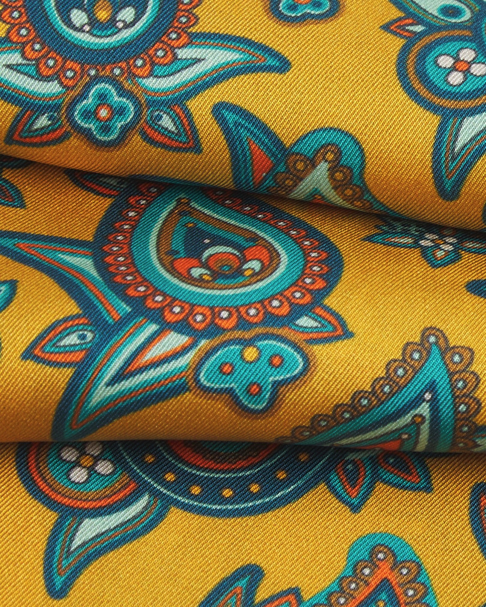 A ruffled close-up of the 'Grassmere' gold silk scarf, presenting the overlapping elements of blue, blue-green, orange, and yellow paisley patterns.