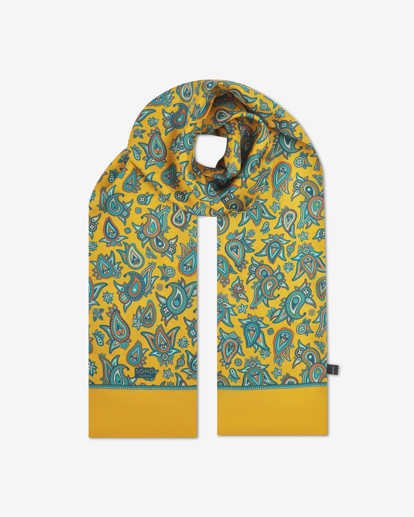 The 'Grassmere' gold silk scarf looped with both ends parallel to effectively display the full repeat pattern of blue, blue-green, orange, and yellow paisley patterns on an gold background.