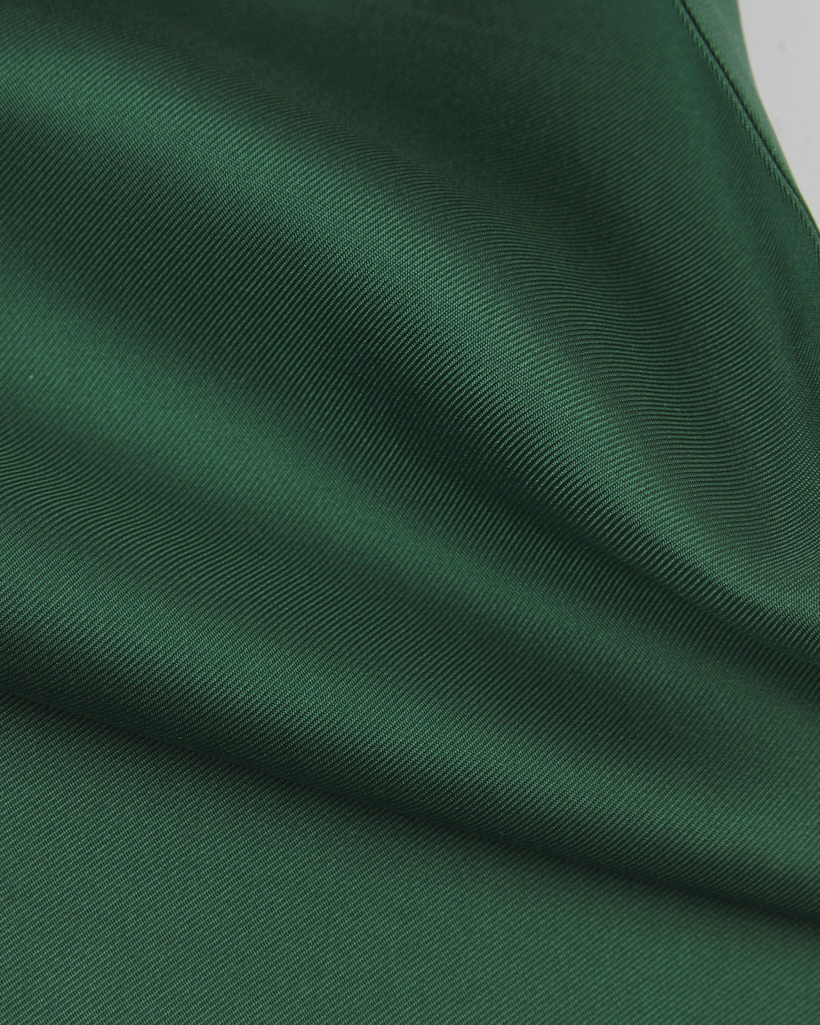 A ruffled close-up of the green silk aviator scarf, presenting the sheen of the fine silk material.