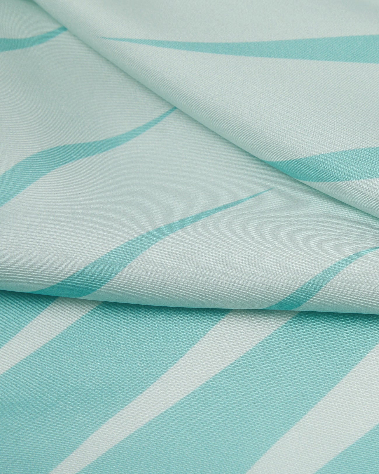 A ruffled close-up of the 'Hamburg' silk neckerchief, presenting a closer view of the waveform-like motif in teal and turquoise.