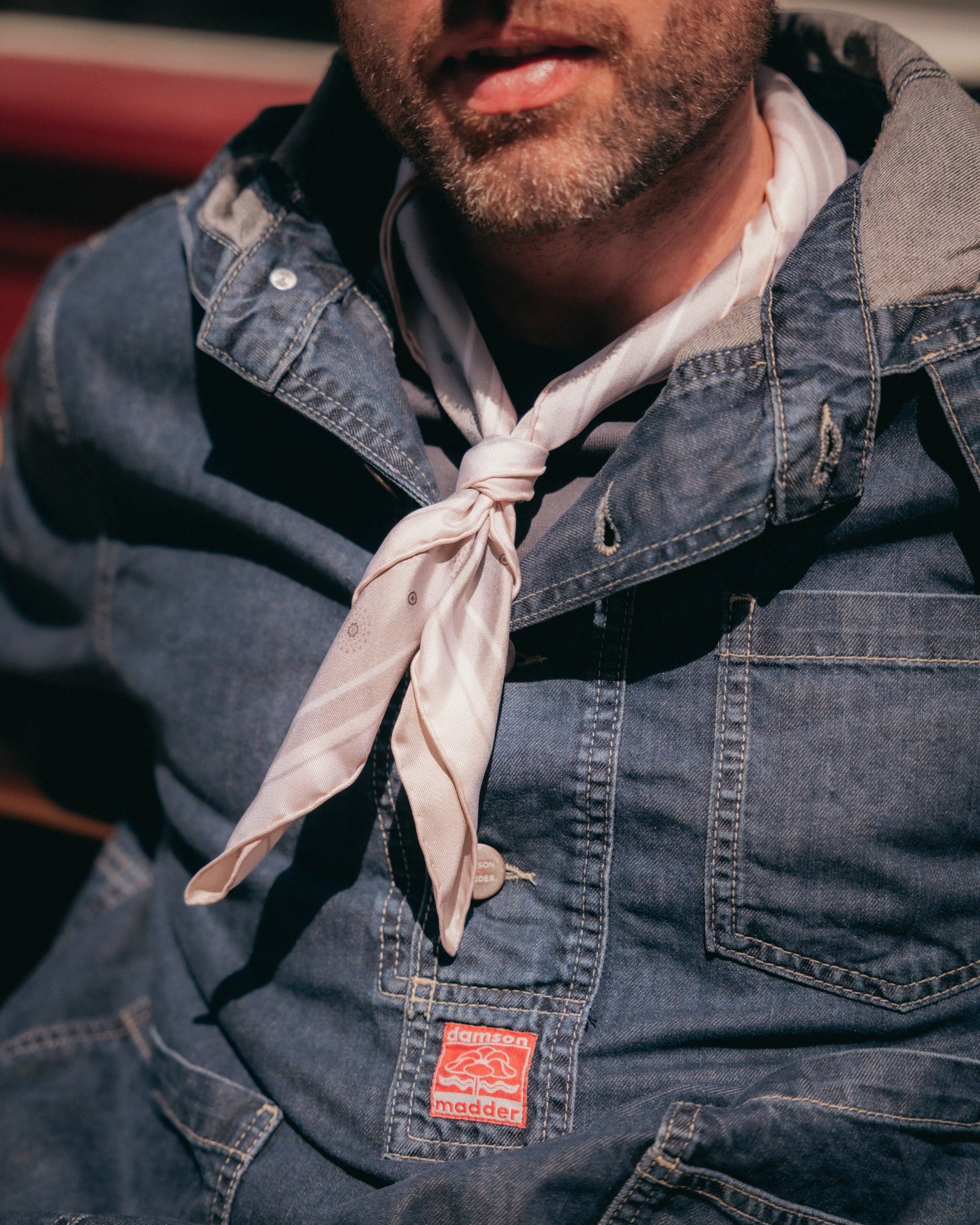 Close-up of man wearing the 'Islington' silk neckerchief in warm grey from SOHO Scarves with a view of the subtle sunburst wheel repeat pattern.