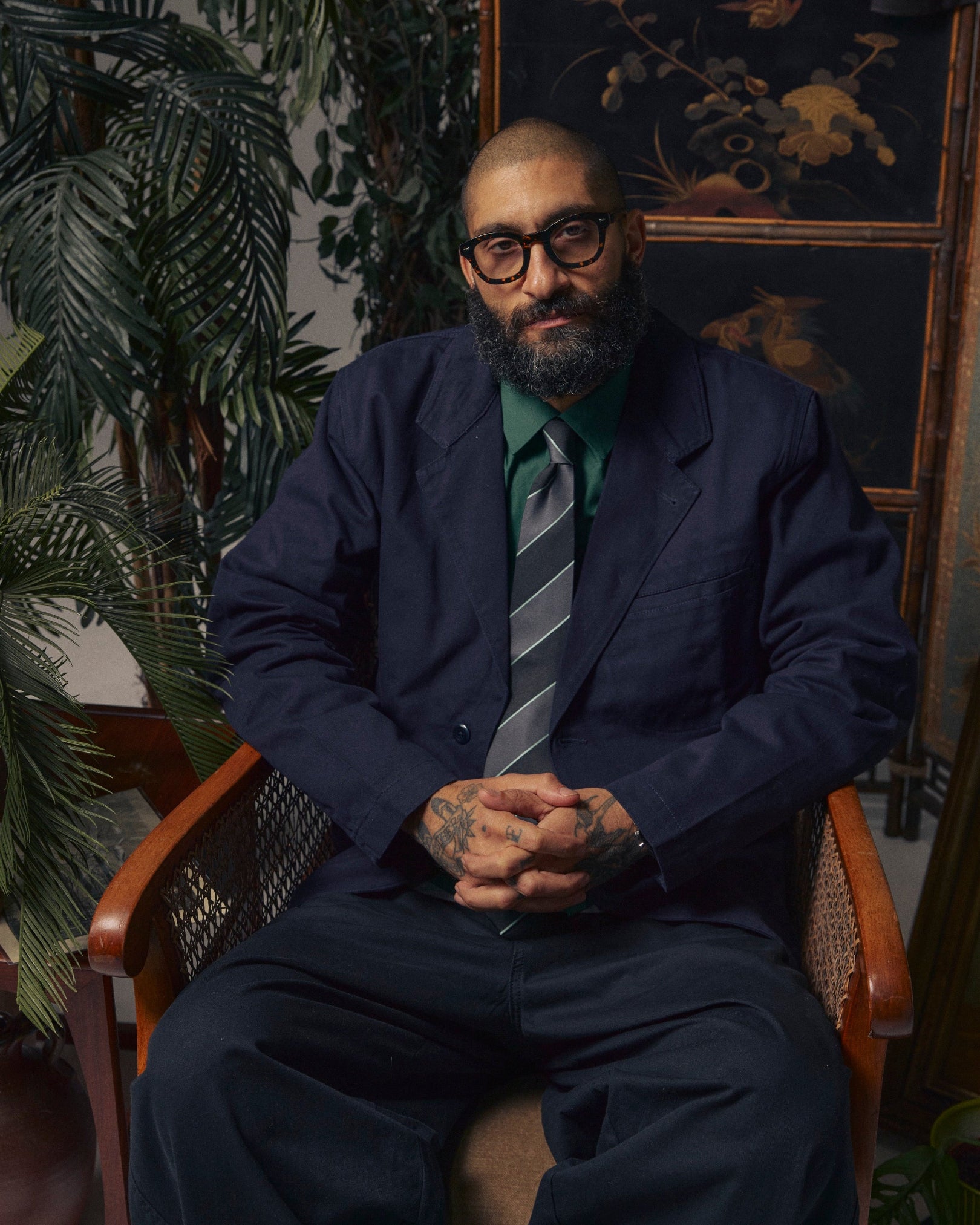 Man wearing the  'Jarrett Gardenia' silk neck tie with grey and black bands with fine teal highlights. Paired with dark blue blazer.