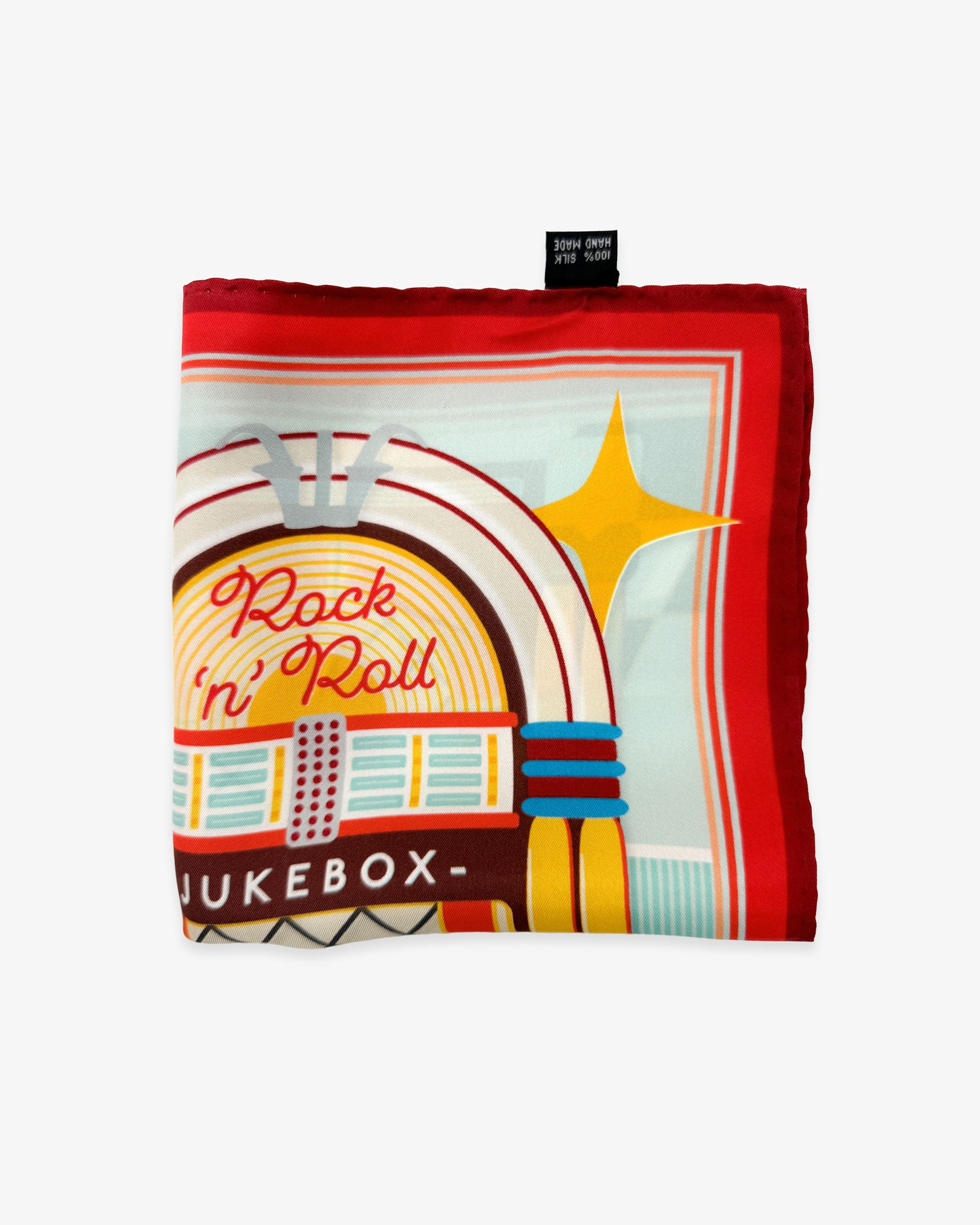 The 'Jukebox 2' silk pocket square from SOHO Scarves folded into a quarter, showing a portion of the iconic 1950's jukebox illustration and red border.