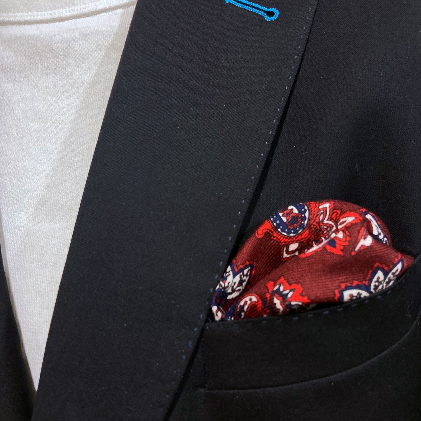 Close-up of 'kovalam' wool pocket square in breast pocket of dark suit jacket.