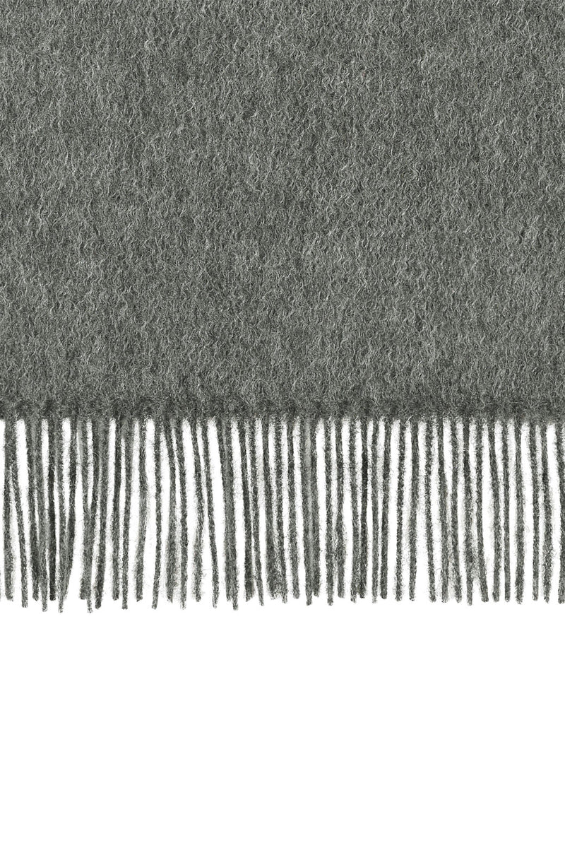 Perfectly horizontal view of the fringe of a light-grey pure cashmere scarf from Soho Scarves against a white background.