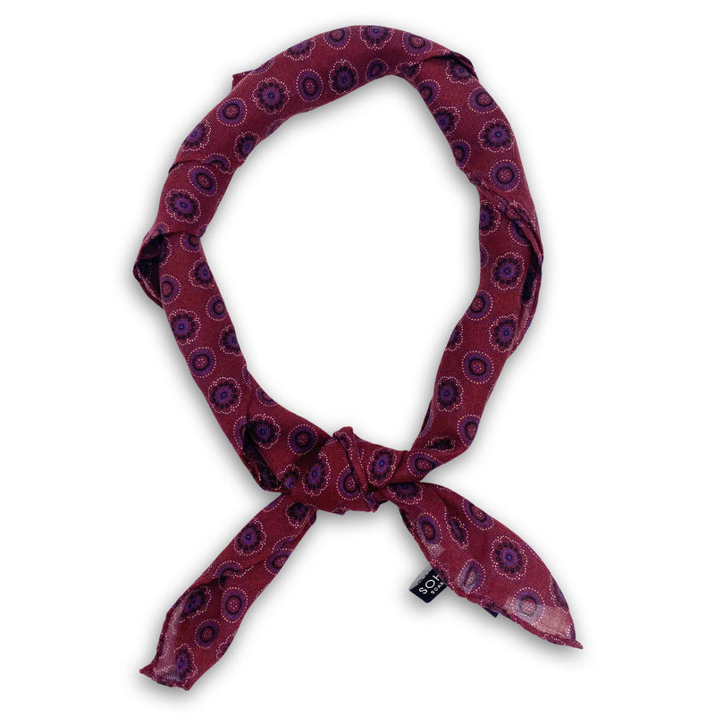'The Seattle' burgundy and blue disc patterned bandana. Knotted into a loop on a white background.