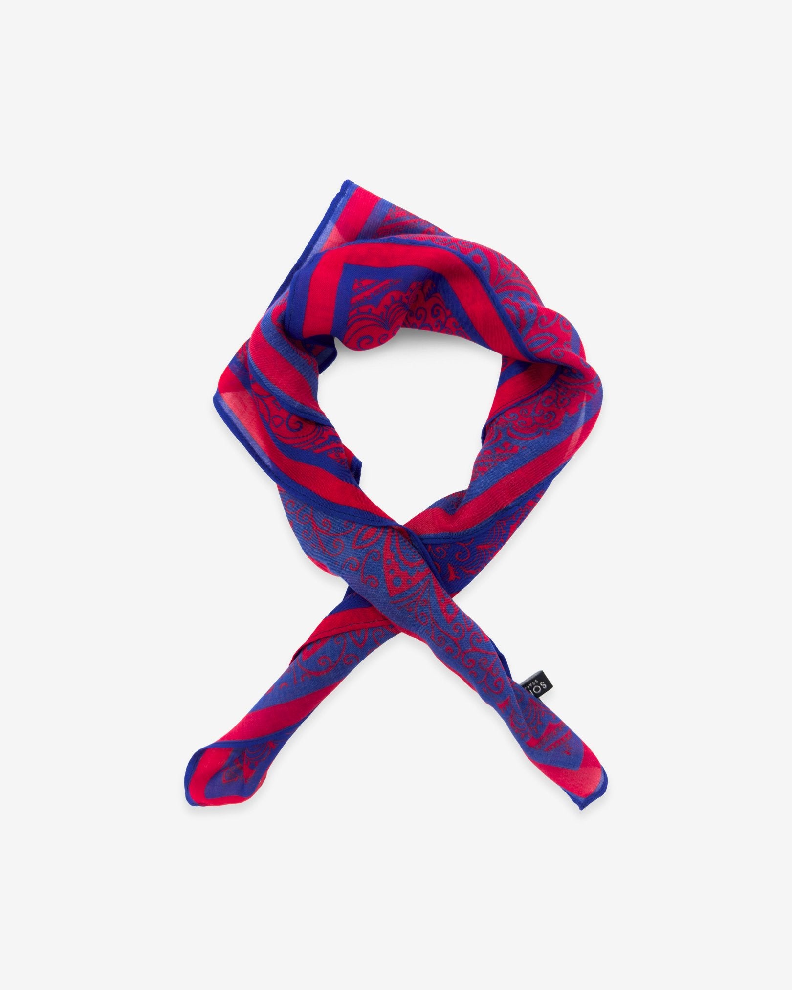 The Torun red bandana featuring a detailed Aztec-inspired pattern in blue. Knotted into a loop against a white background.