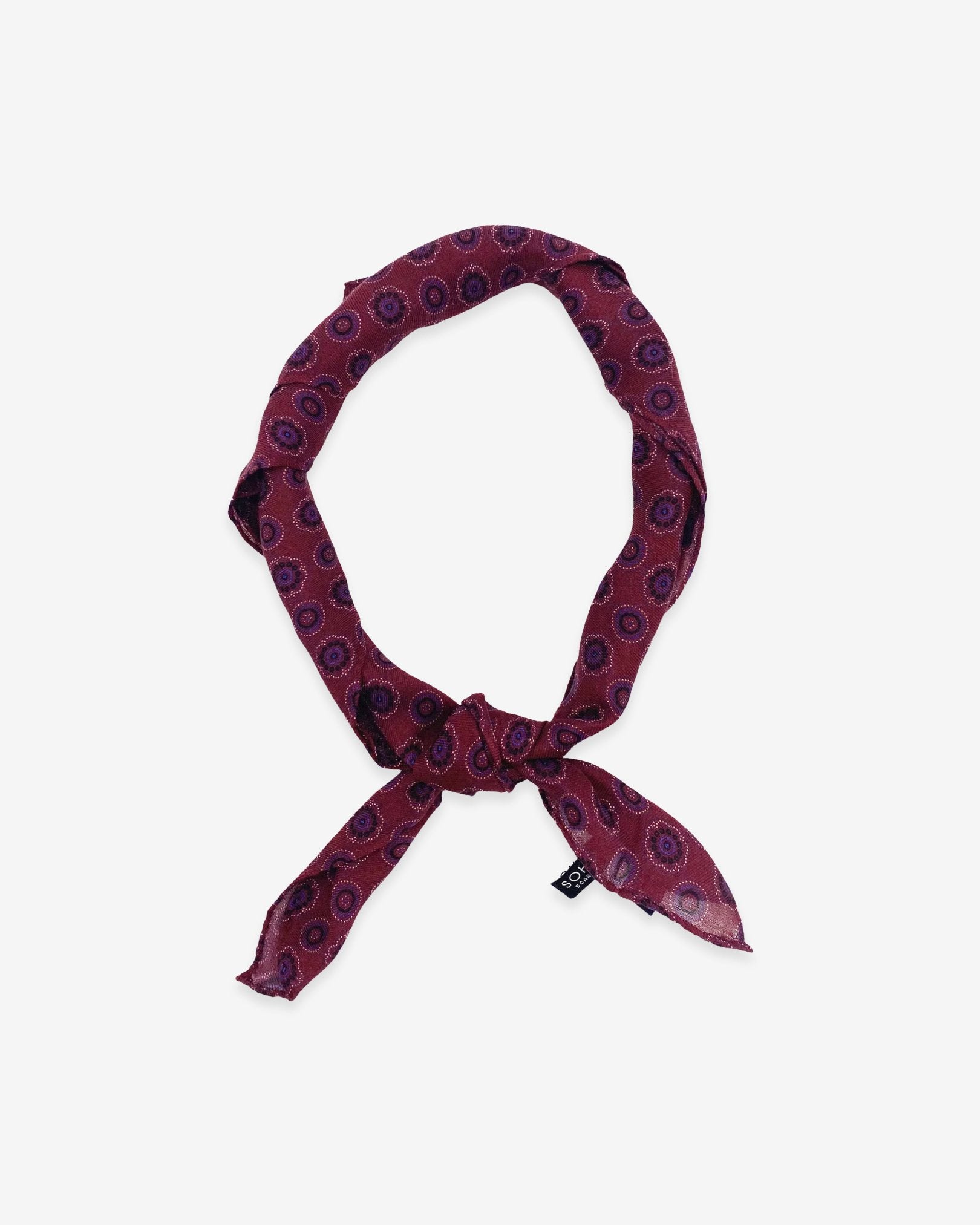 'The Seattle' burgundy and blue disc patterned bandana. Knotted into a loop on a white background.