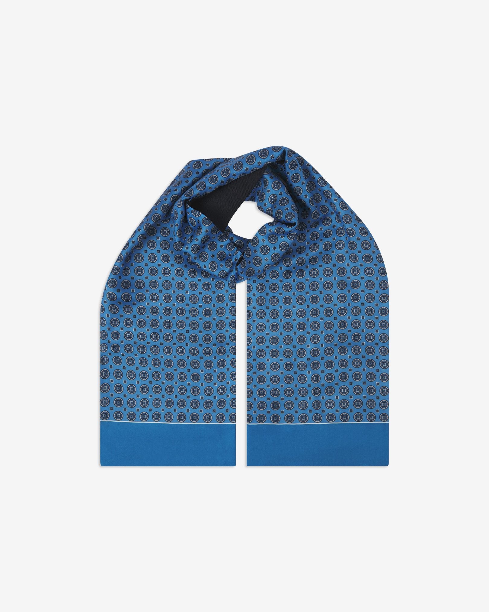 The Kyoto wool-backed silk scarf. Unravelled and looped in the middle, highlighting the length, width and circular pattern on silk. Also showing the solid blue borders.