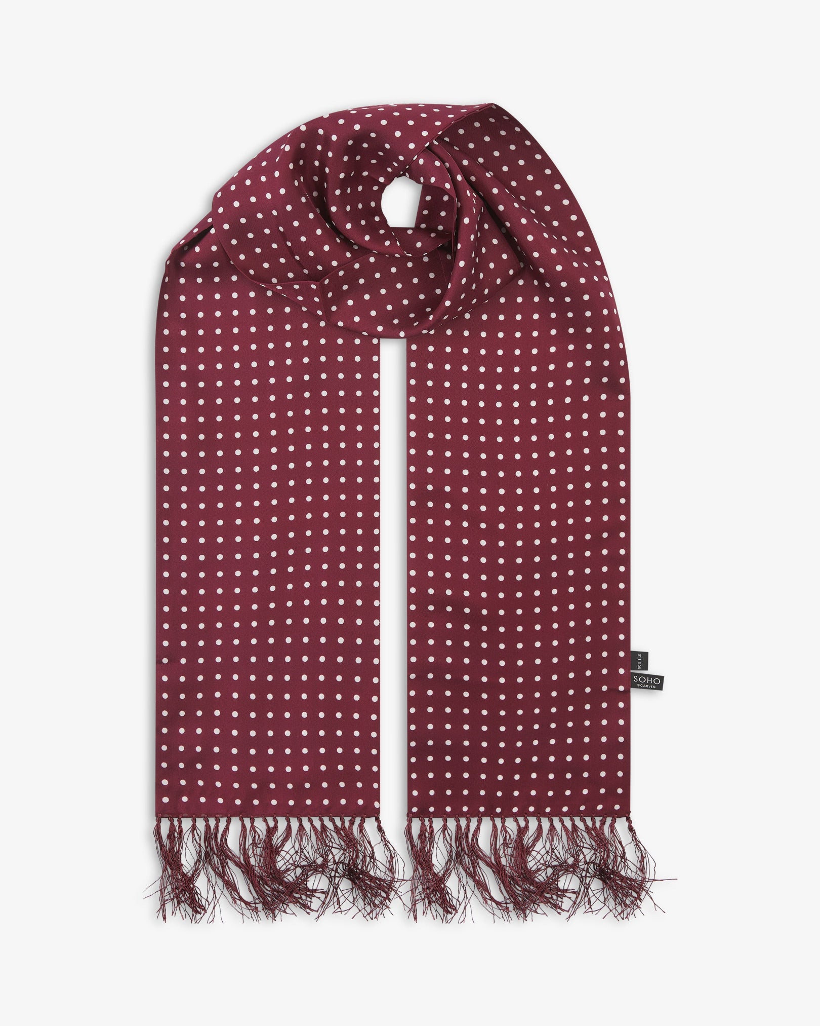 The Sapporo pure silk aviator scarf looped in middle with both ends parallel showing the polka dot design in deep maroon with white dots and matching 3-inch fringe.