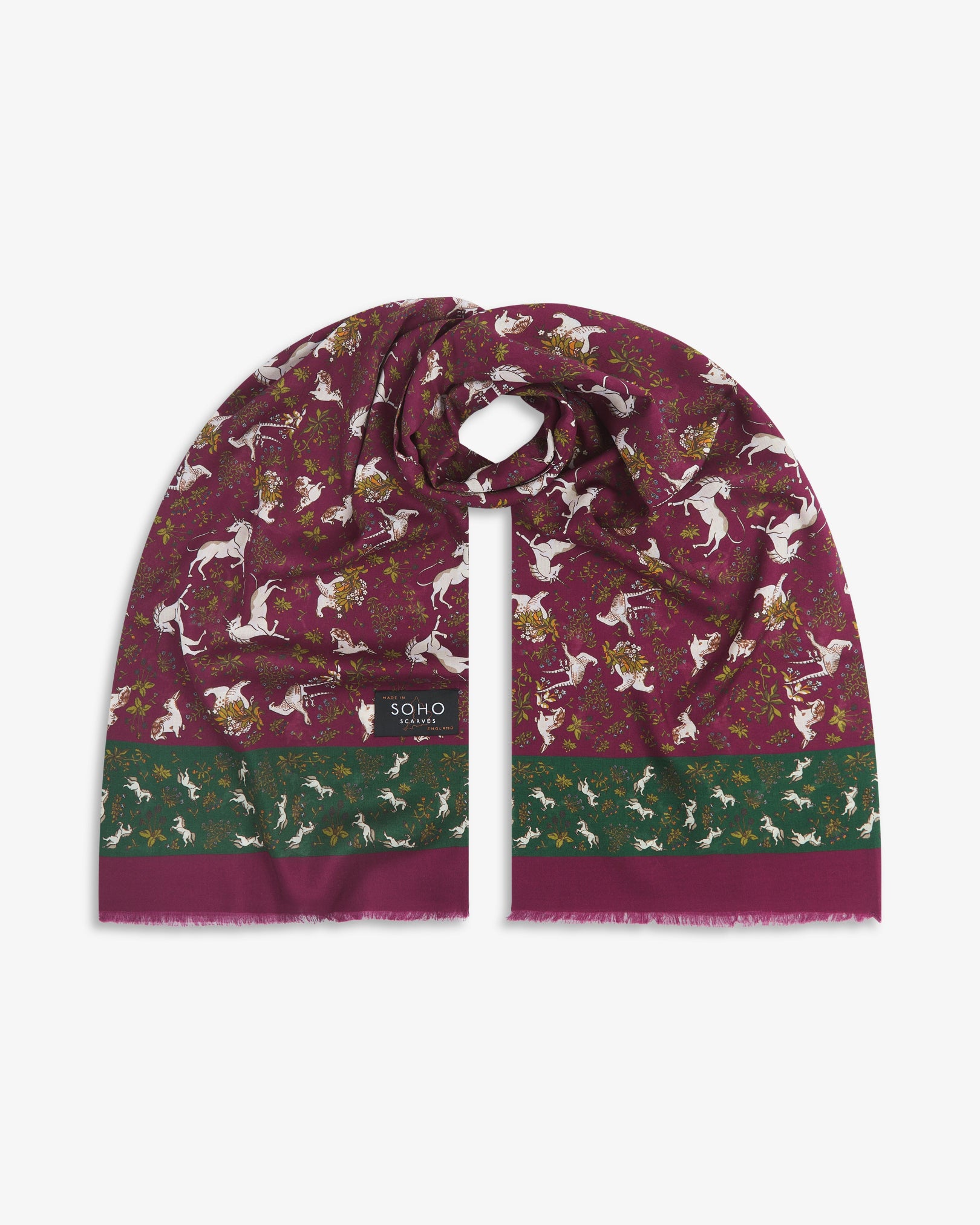 Premium wine and green silk-wool scarf depicting animals amid botanical forms. Unravelled and looped in the middle, presenting slightly longer and wider scarf dimensions, ornate border and 'Soho Scarves' label.