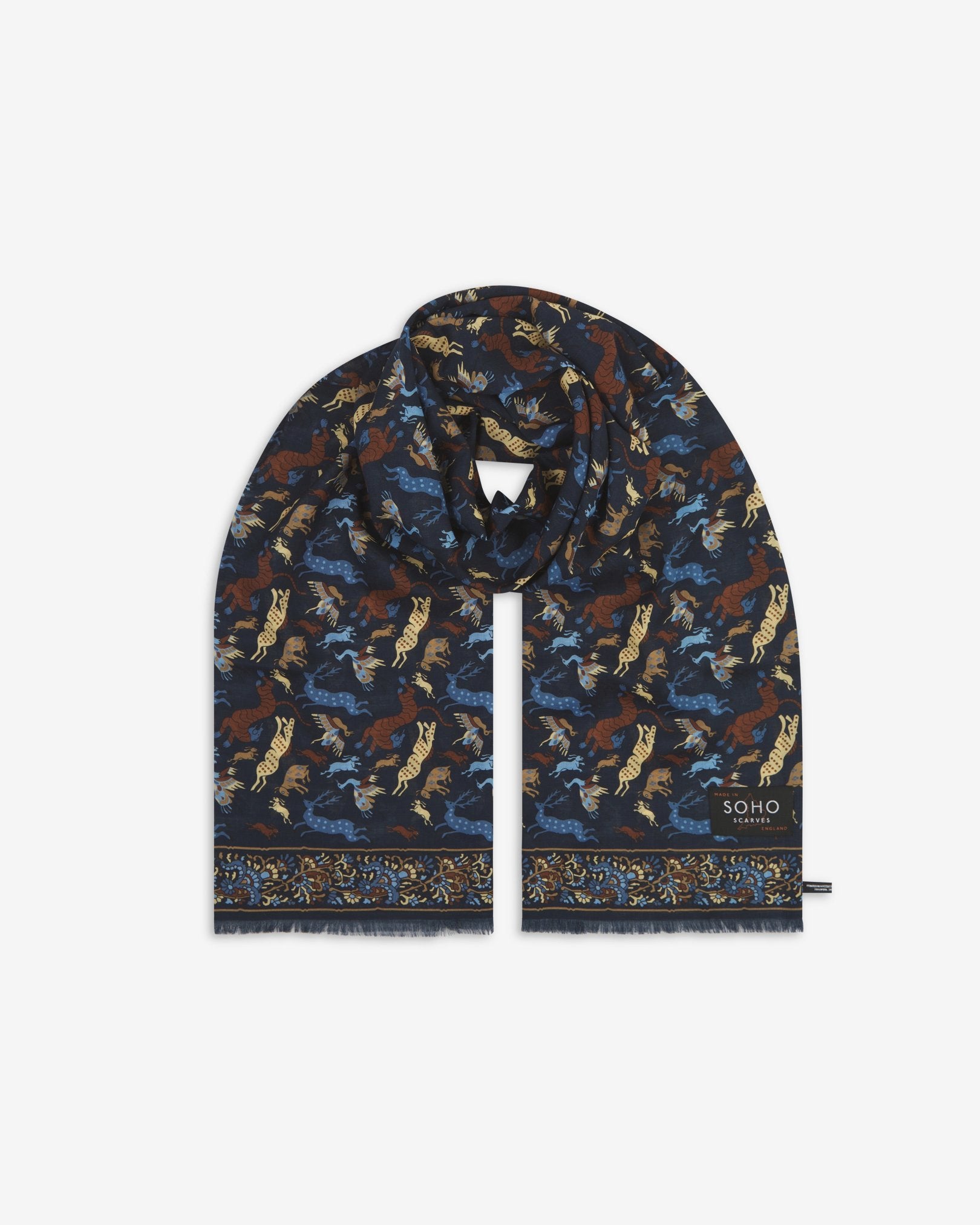 Premium ‘Airforce-blue’ silk-wool scarf with stylised woodland creatures. Unravelled and looped in the middle, presenting slightly longer and wider scarf dimensions, ornate border, eyelash fringing and ‘Soho Scarves’ label.