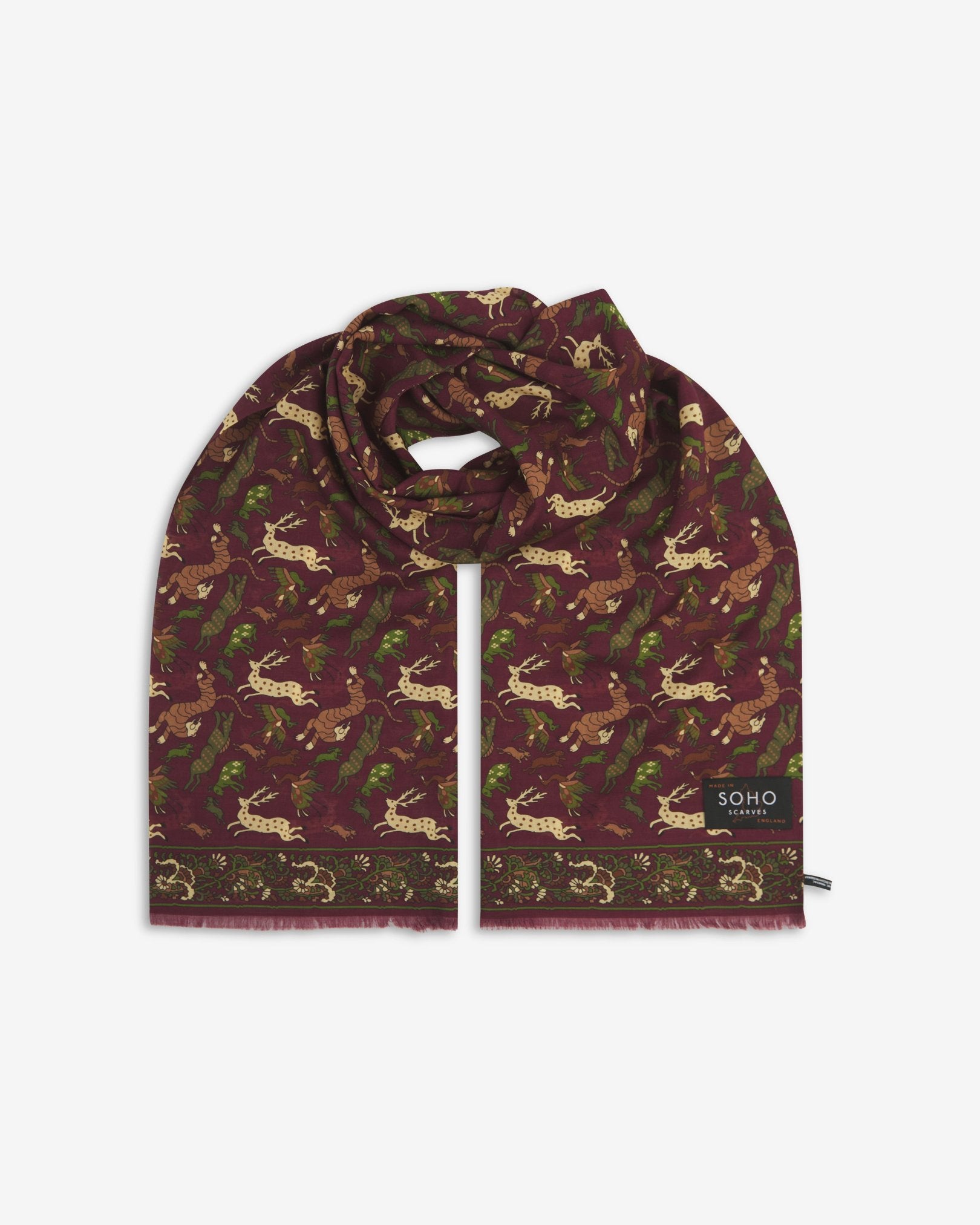 Premium burgundy silk-wool scarf with stylised woodland creatures. Unravelled and looped in the middle, presenting slightly longer and wider scarf dimensions, ornate border, eyelash fringing and ‘Soho Scarves’ label.