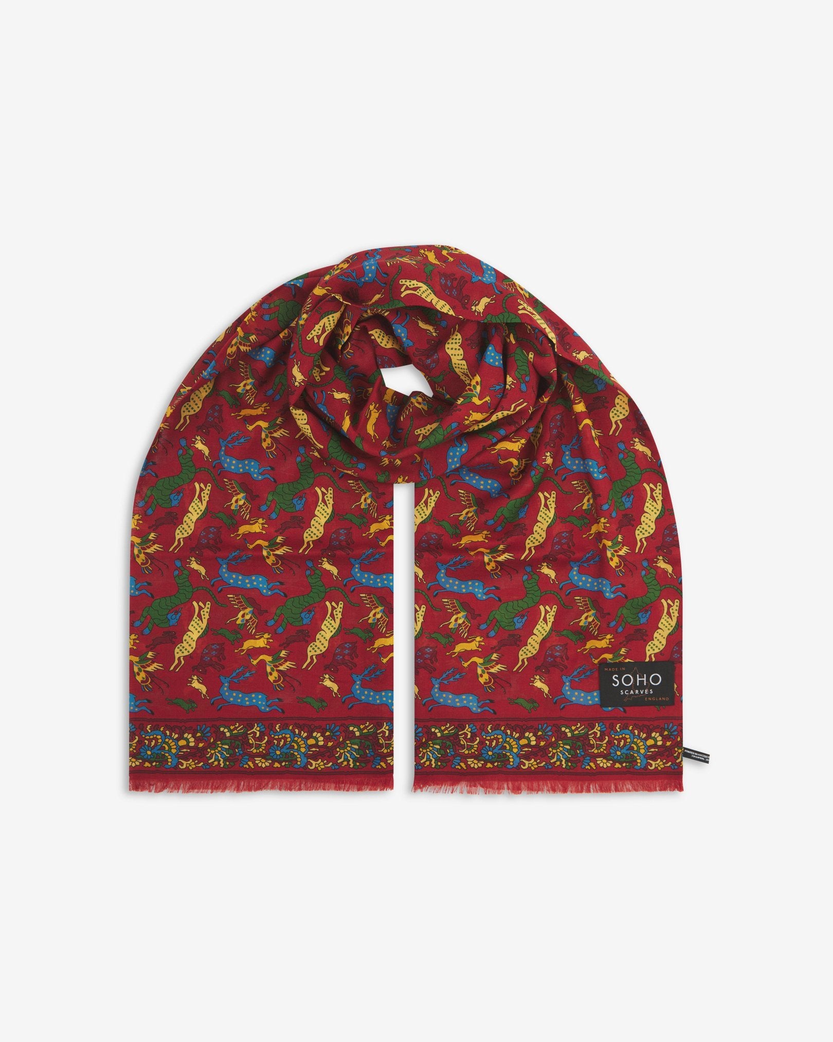 Premium ‘rust-red’ silk-wool scarf with stylised woodland creatures. Unravelled and looped in the middle, presenting slightly longer and wider scarf dimensions, ornate border, eyelash fringing and ‘Soho Scarves’ label.