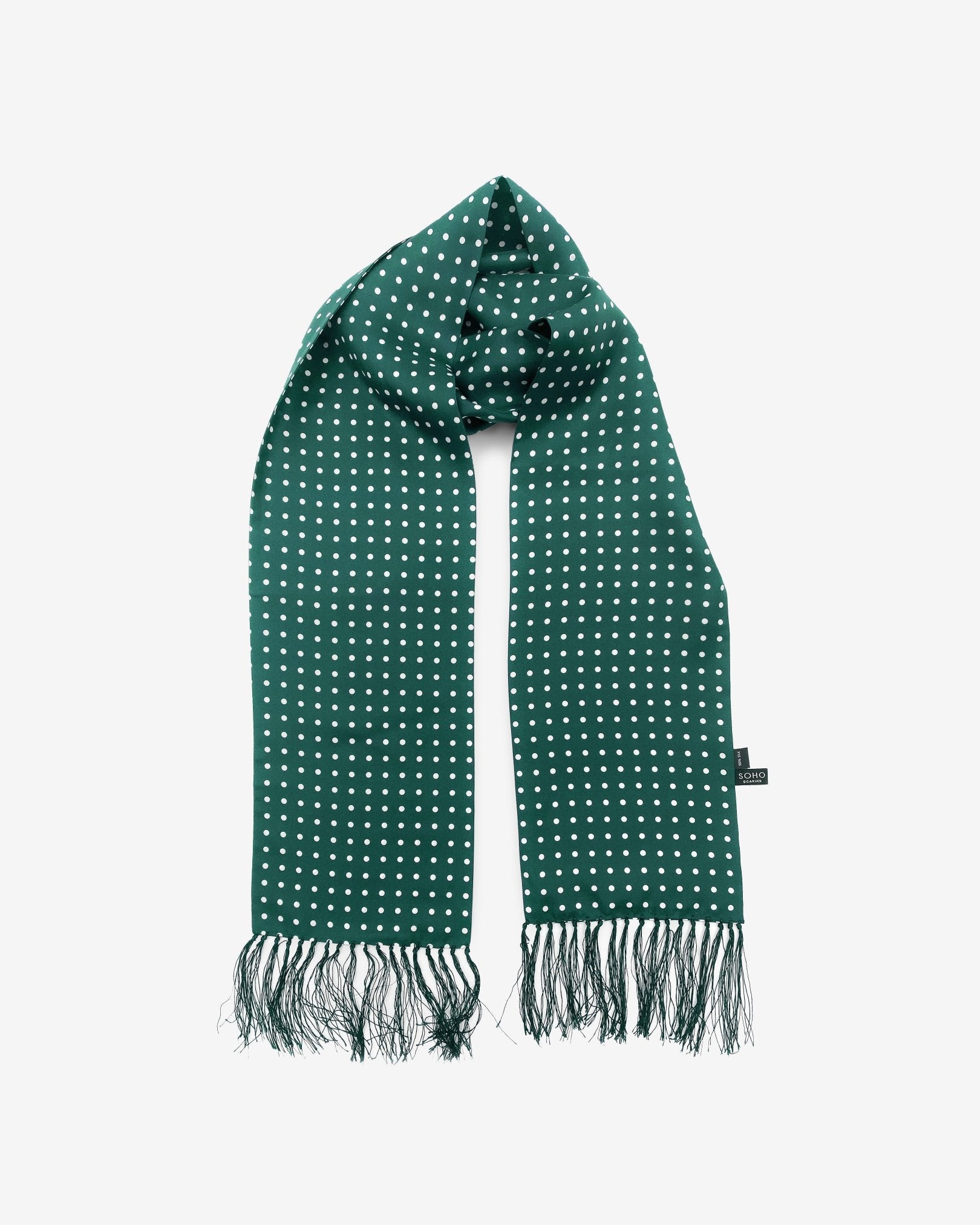 The 'Westminster Rg' racing green silk aviator scarf with white polka-dot patterns.  Looped in middle with both ends parallel, clearly showing the racing green 3-inch fringe and the 'Soho Scarves' label on the right edge.