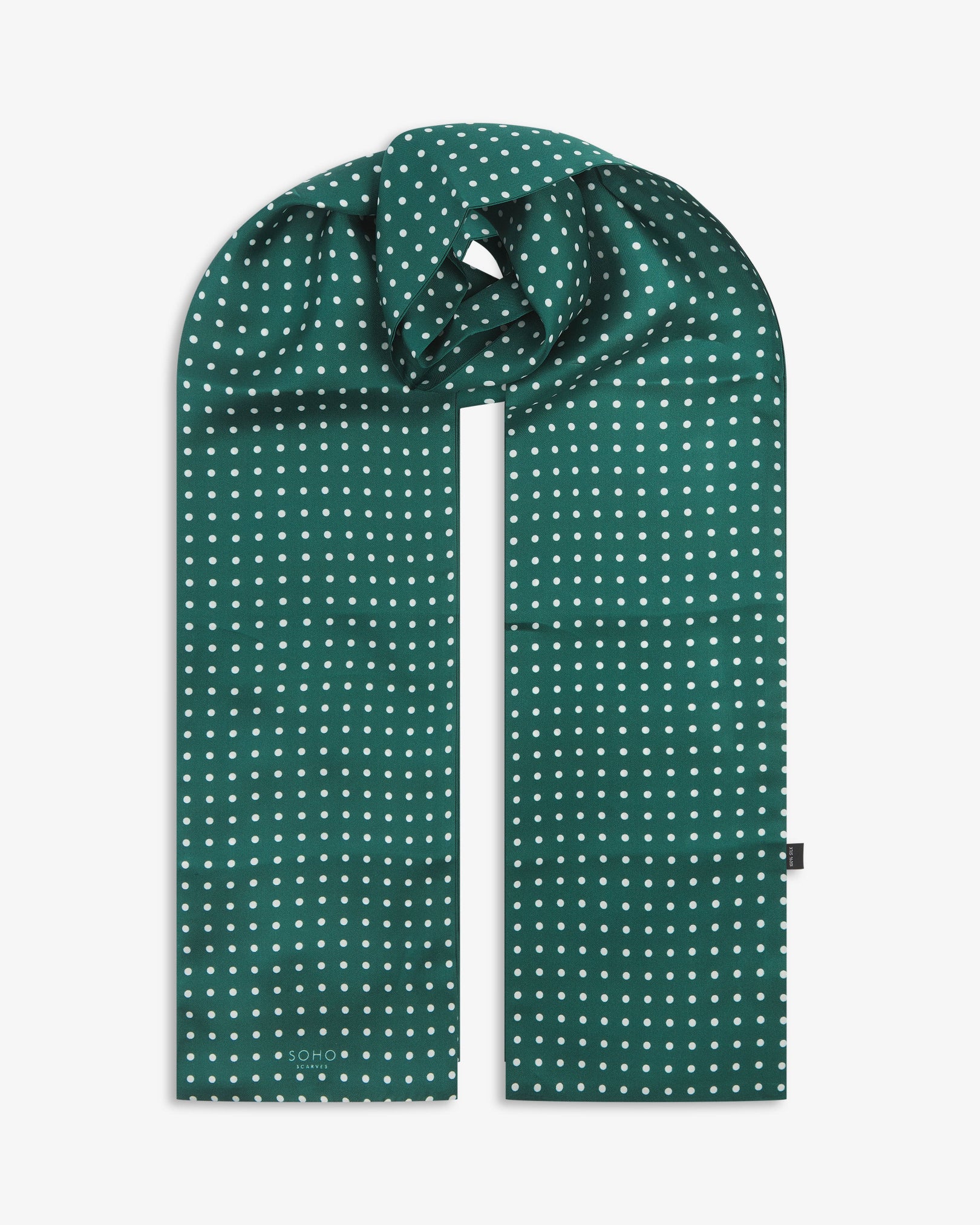 The 'Westminster Rg' racing green silk scarf with white polka-dot patterns.  Looped in middle with both ends parallel showing the the 'Soho Scarves' label on the right edge.