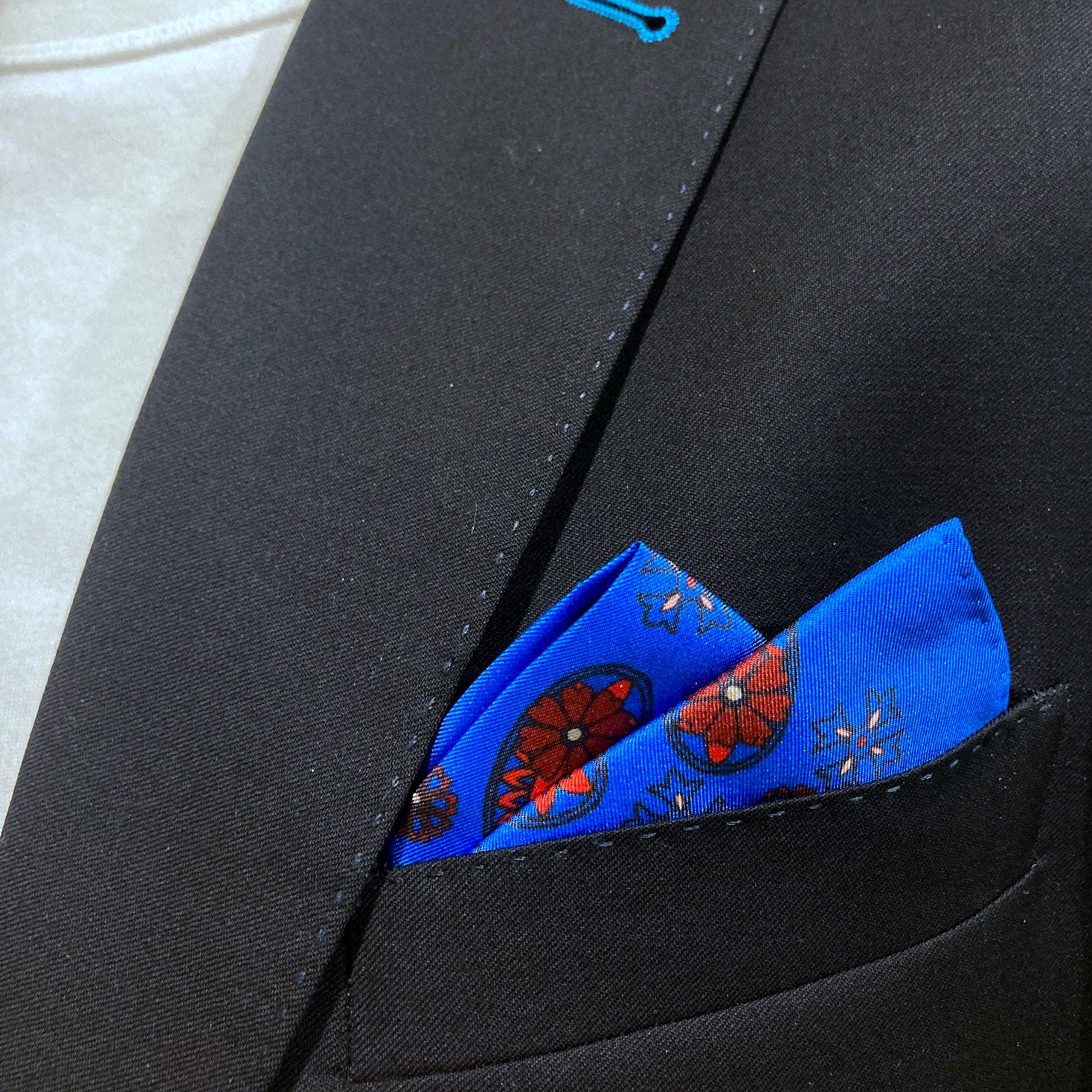 Close-up of 'Marrakesh' silk pocket square in breast pocket of dark suit jacket.