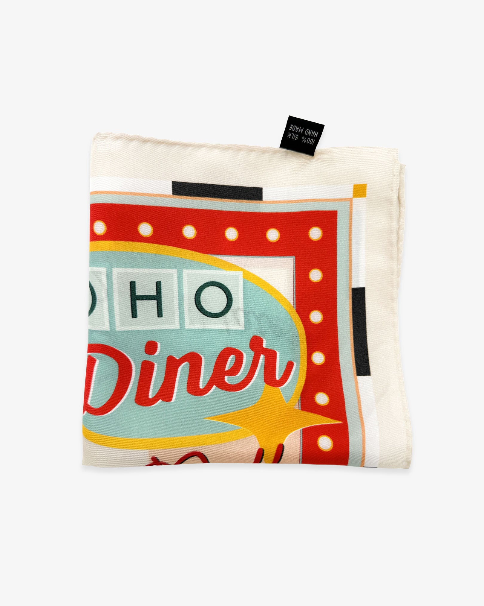 The 'Milkshake' on chalk silk pocket square from SOHO Scarves folded into a quarter, showing a portion of the 1950's diner aesthetic and chalk-coloured border.