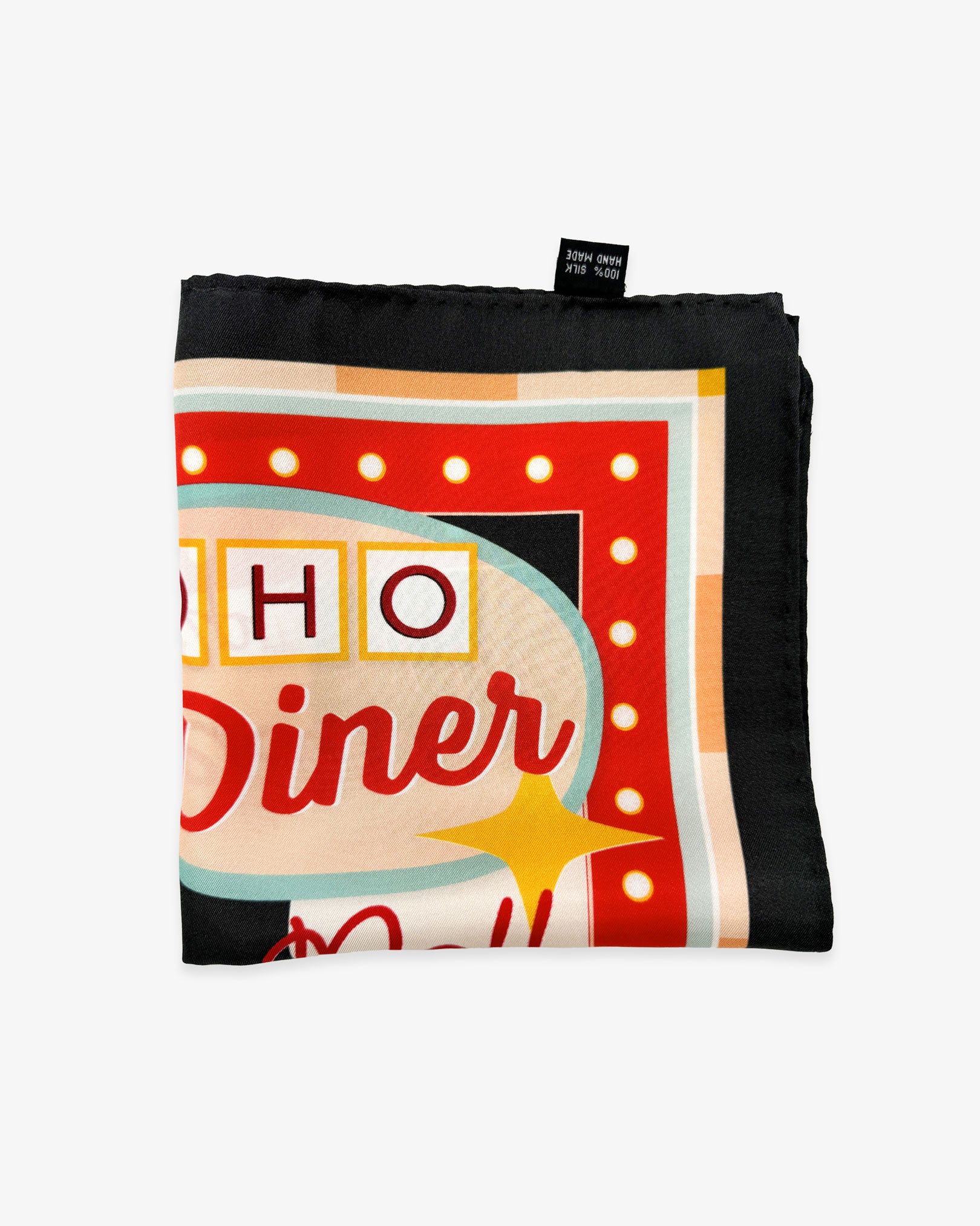 The 'Milkshake' on charcoal silk pocket square from SOHO Scarves folded into a quarter, showing a portion of the 1950's diner aesthetic and charcoal border.