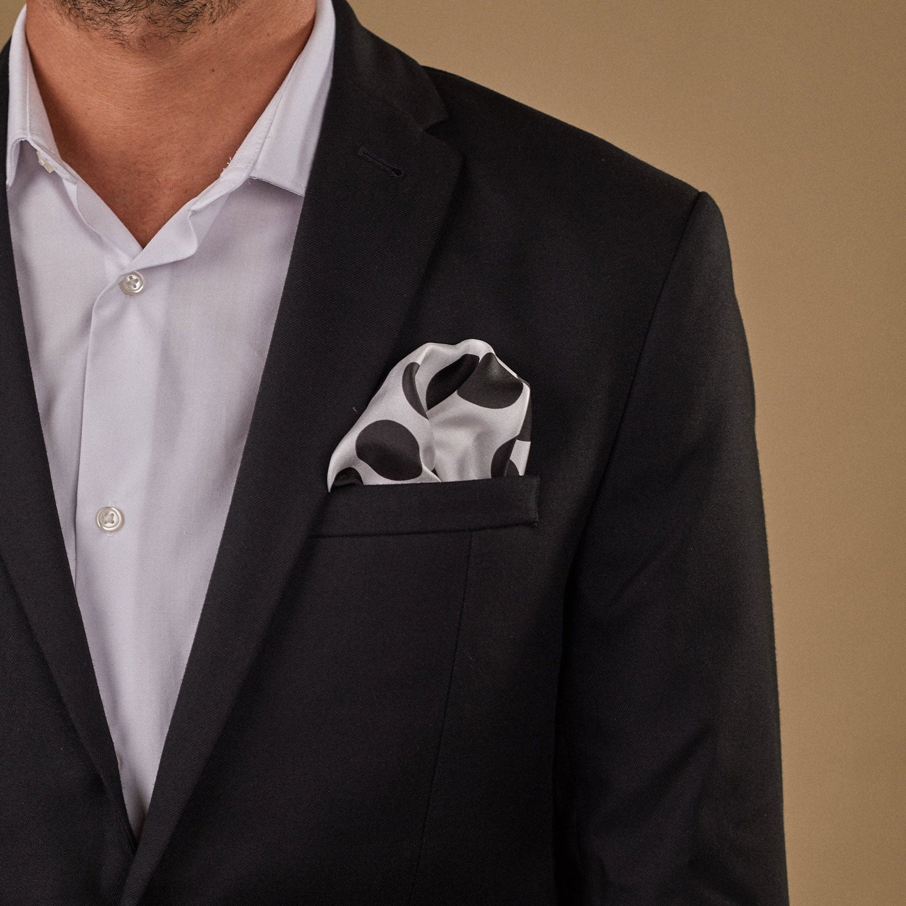 Model with black spotted 'Chaney' silk pocket square in breast pocket of dark suit jacket.
