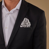 Model with 'Keaton' silk pocket square with white disc patterns in breast pocket of dark suit jacket.