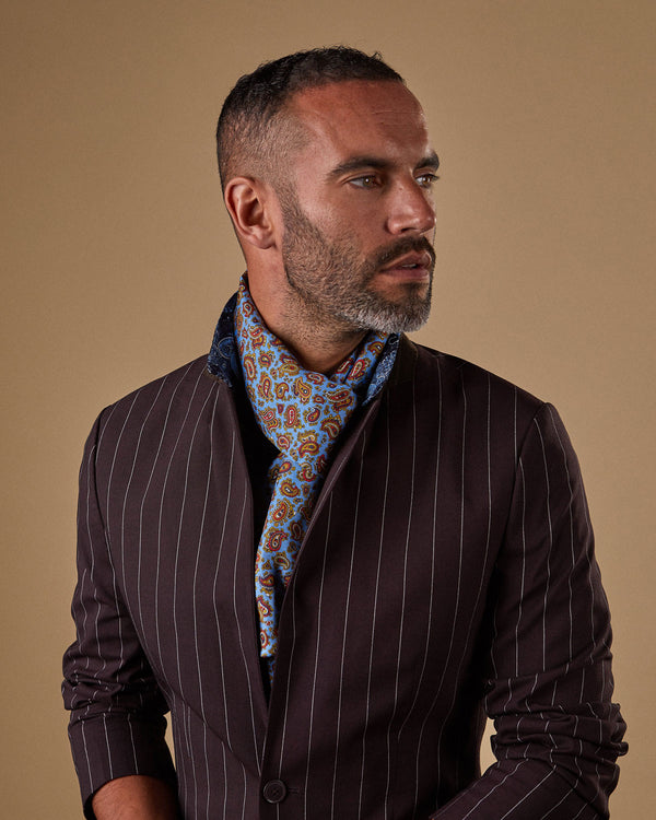 'The Regent' paisley polyester scarf snugly wrapped around model's neck and ends partially tucked under dark, pinstripe suit.