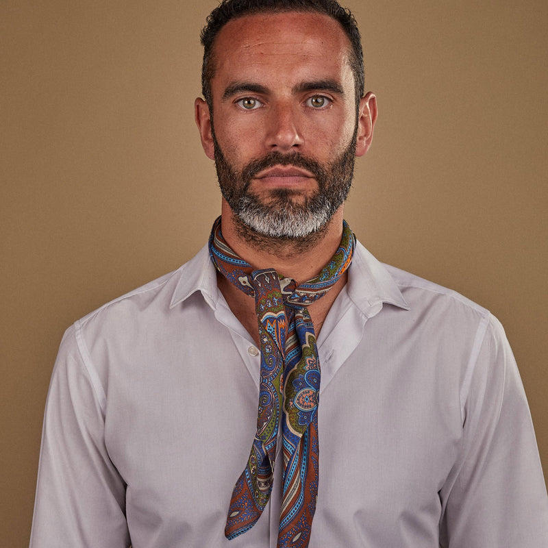 Wearing 'The Montreal' multicoloured paisley patterned bandana. Tied snugly around neck in a simple knot and paired with a white shirt.