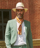 Wearing 'The Niagra' pure silk, orange and pink floral scarf in a simple Parisian knot and paired with a mint-green casual suit.